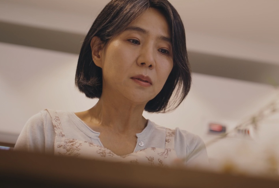 A Bae Yoon-ok olhando para baixo, com expressão pensativa