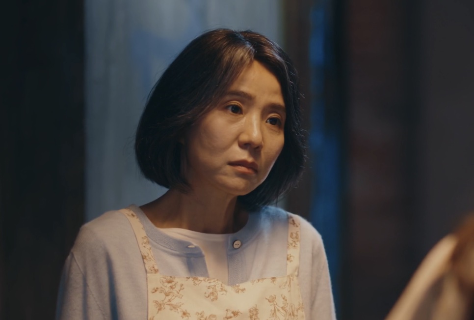 A Bae Yoon-ok com expressão séria, numa cena à noite