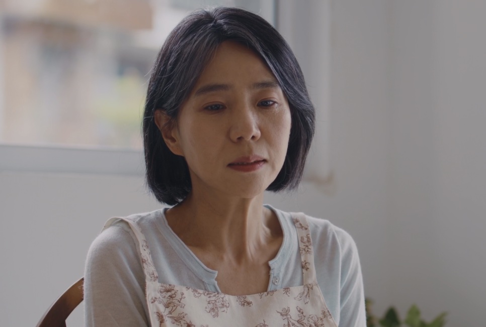A Bae Yoon-ok perto da janela, de olhar triste