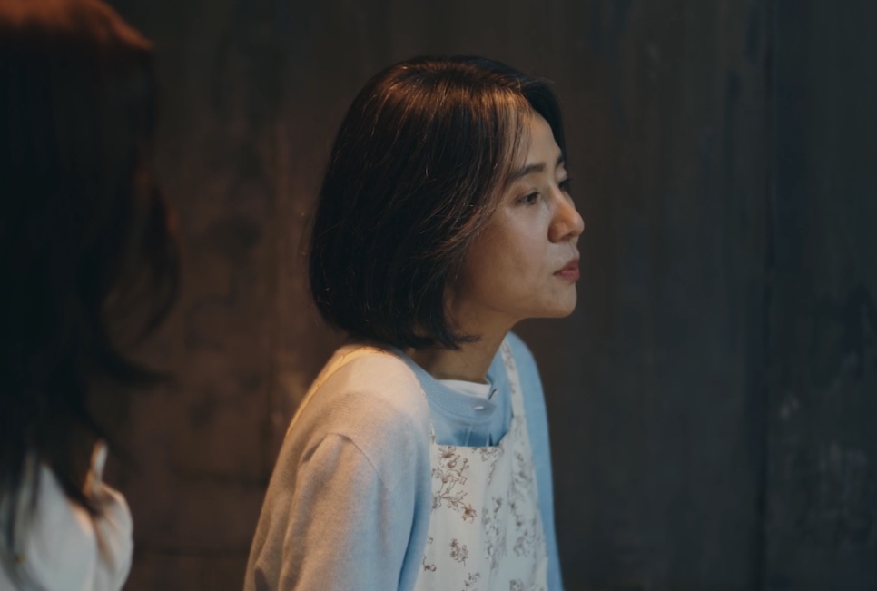 A Bae Yoon-ok de perfil, numa cena escura
