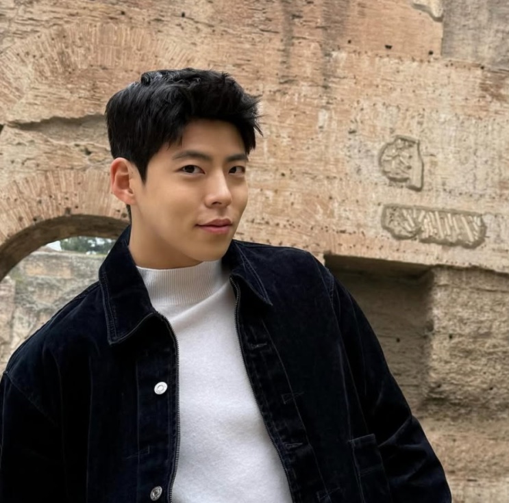 Choi Woo-sung diante de um muro de pedra