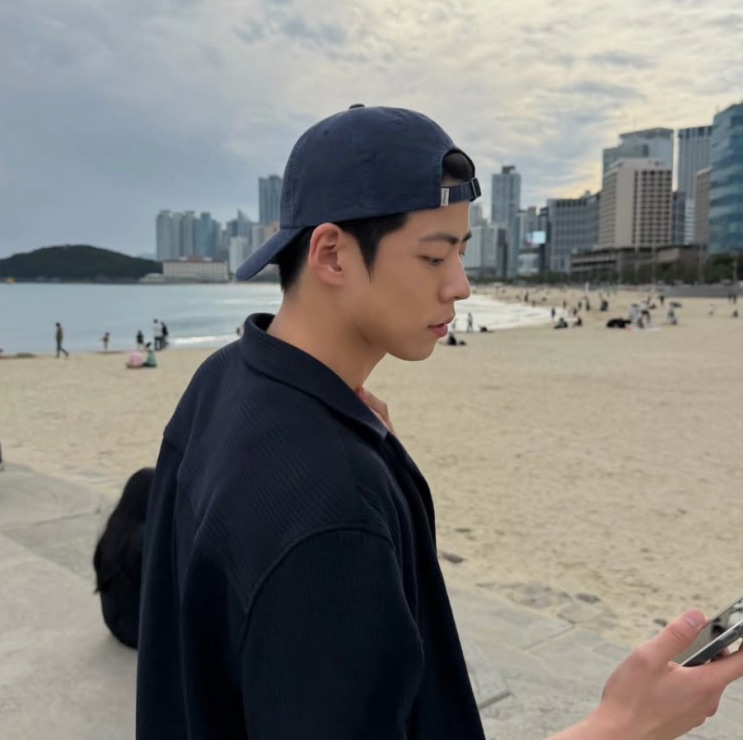 Choi Woo-sung de boné, numa praia