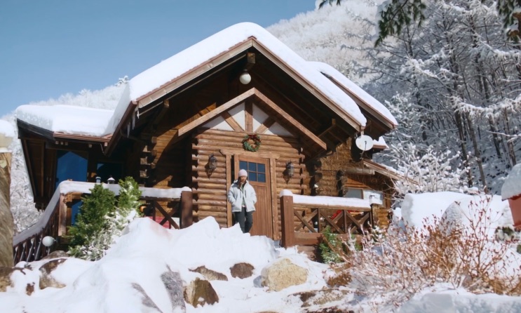 A cabana de frente, com o telhado e o jardim cobertos de neve