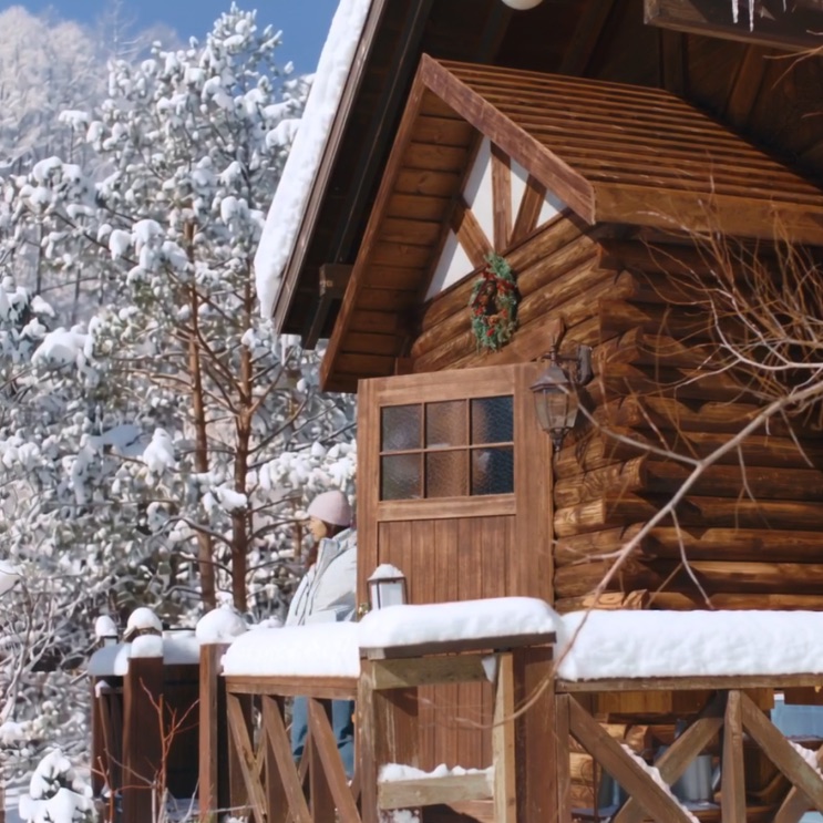 A cabana de troncos ao amanhecer, com neve nos galhos em volta