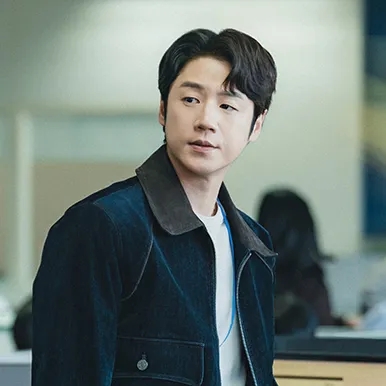 Kwon Tae-seong de jaqueta jeans, dentro da redação