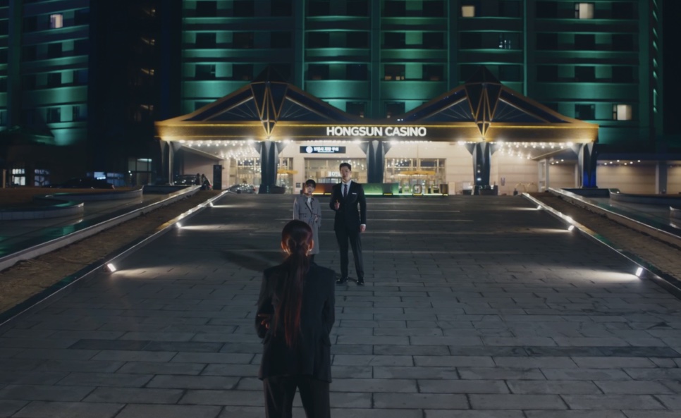 Entrada iluminada do Hongsun Casino à noite, com duas pessoas caminhando na alameda