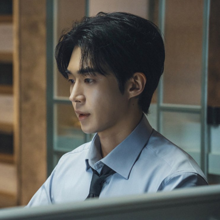 Gi Yeong-do de camisa social, de perfil, olhando para a tela do computador