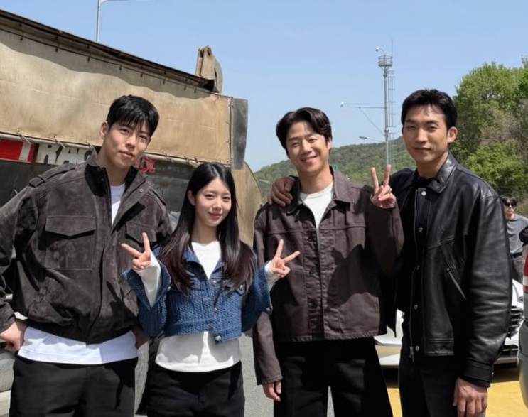 Han Chae-rin com três colegas de elenco em foto de bastidores, na frente de um caminhão
