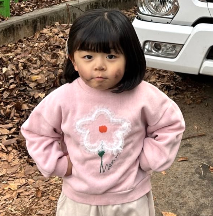 A menina de moletom rosa em pé, ao ar livre