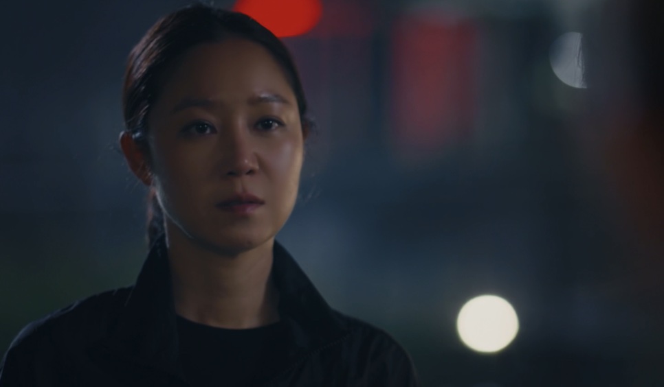 Yu Bo-na, personagem da Gong Hyo-jin, de jaqueta preta, séria, numa rua à noite