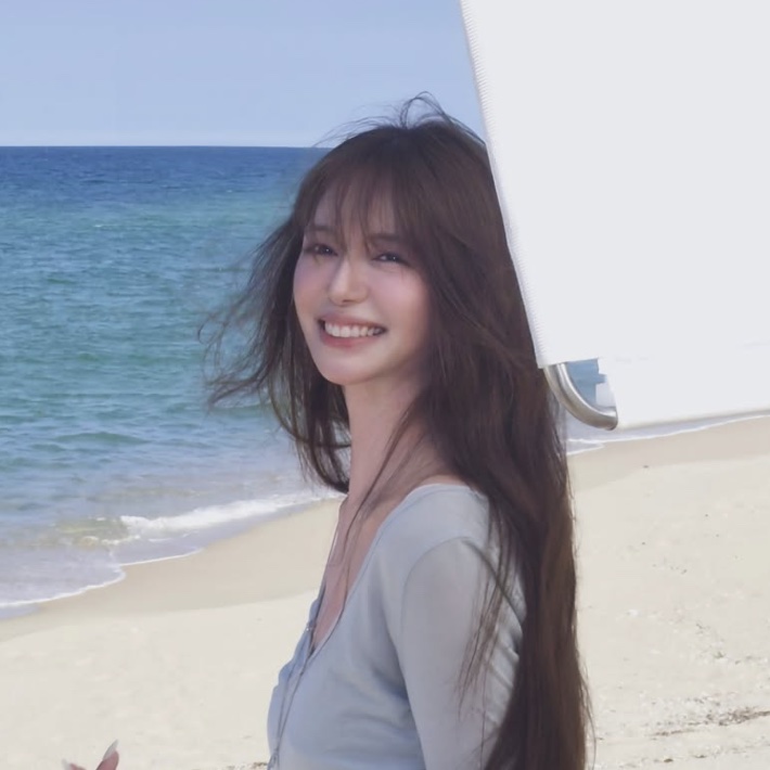 Lee Elijah sorrindo numa praia, com o cabelo ao vento