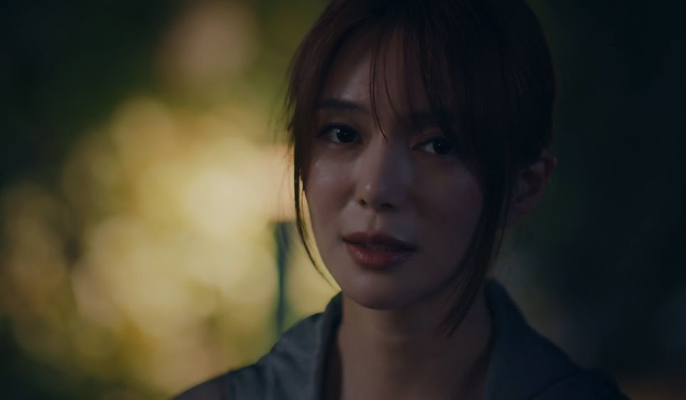 Close da Layla, personagem da Lee Elijah, numa cena escura com luzes desfocadas ao fundo