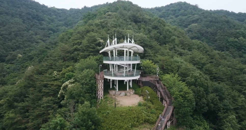 O mirante Hak, uma torre branca com passarelas, no topo de um morro cheio de árvores