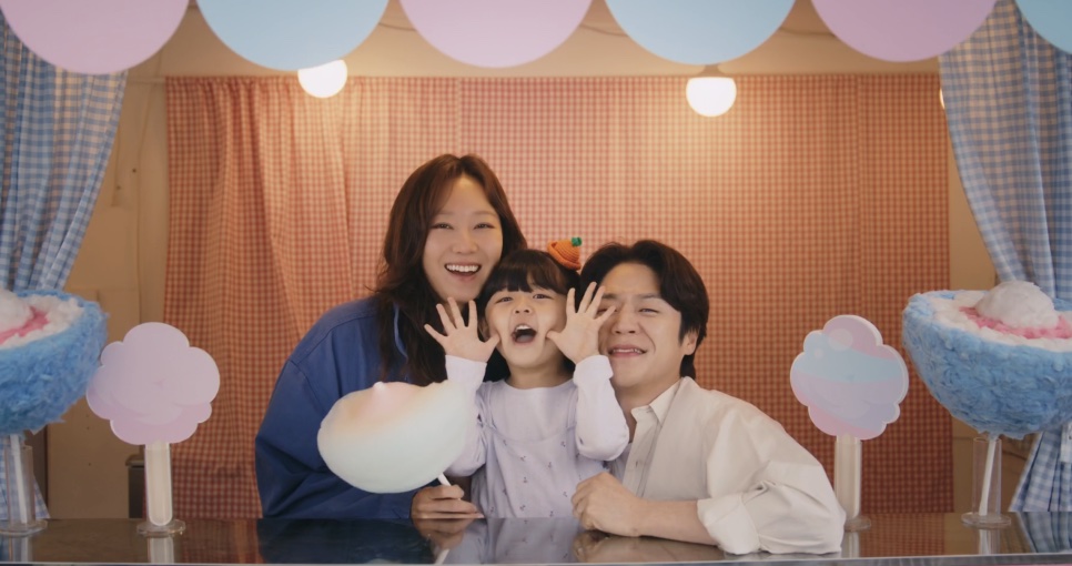 Yu Bo-na, a pequena Yul e Kwon Tae-seong sorrindo juntos numa barraca de algodão-doce