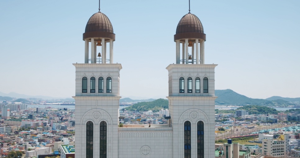 As duas torres brancas da igreja, com cúpulas marrons e a cidade ao fundo