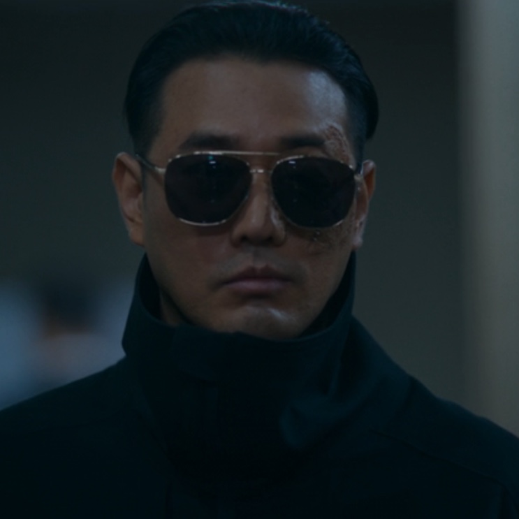 O Bale (Jo Han-sun) de óculos escuros, com a cicatriz no rosto, em A Shop for Killers