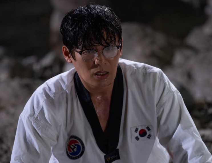 Seong Han-su suado, de uniforme de taekwondo, olhando para baixo