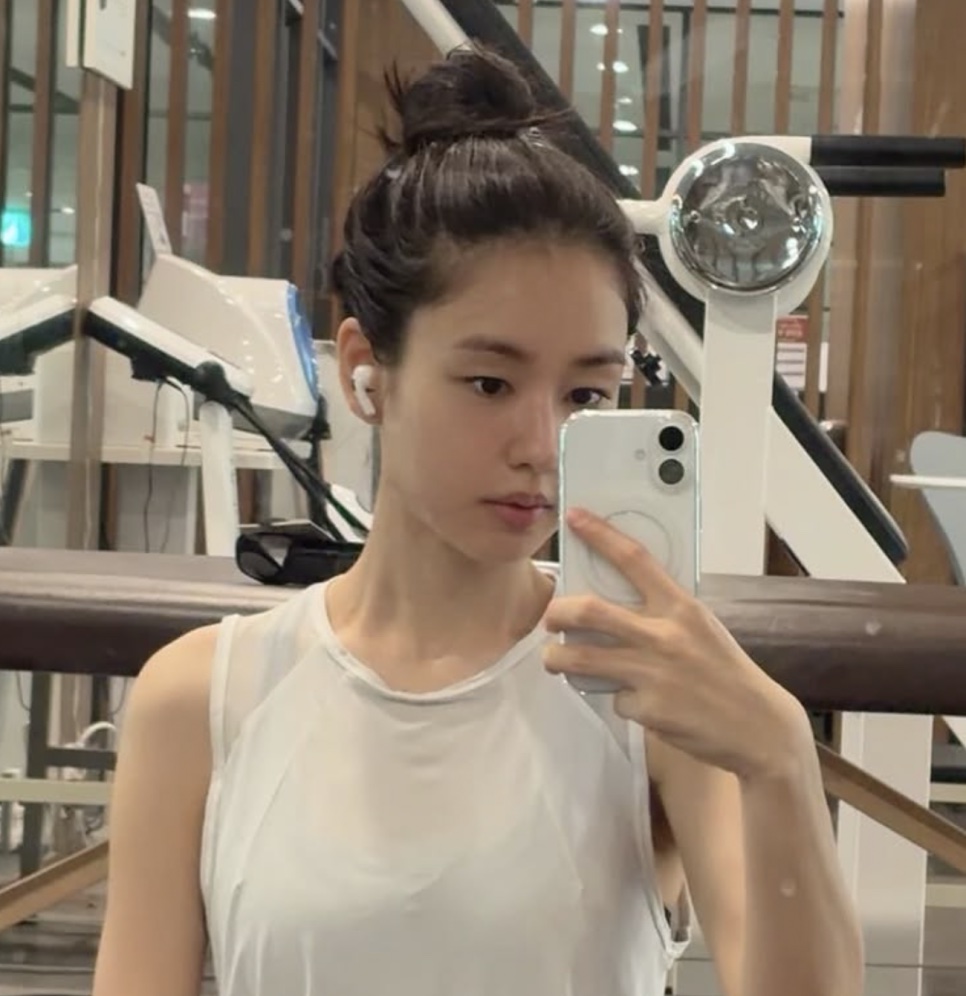 Ahn Eun-jin de coque e regata branca, tirando selfie no espelho de uma academia