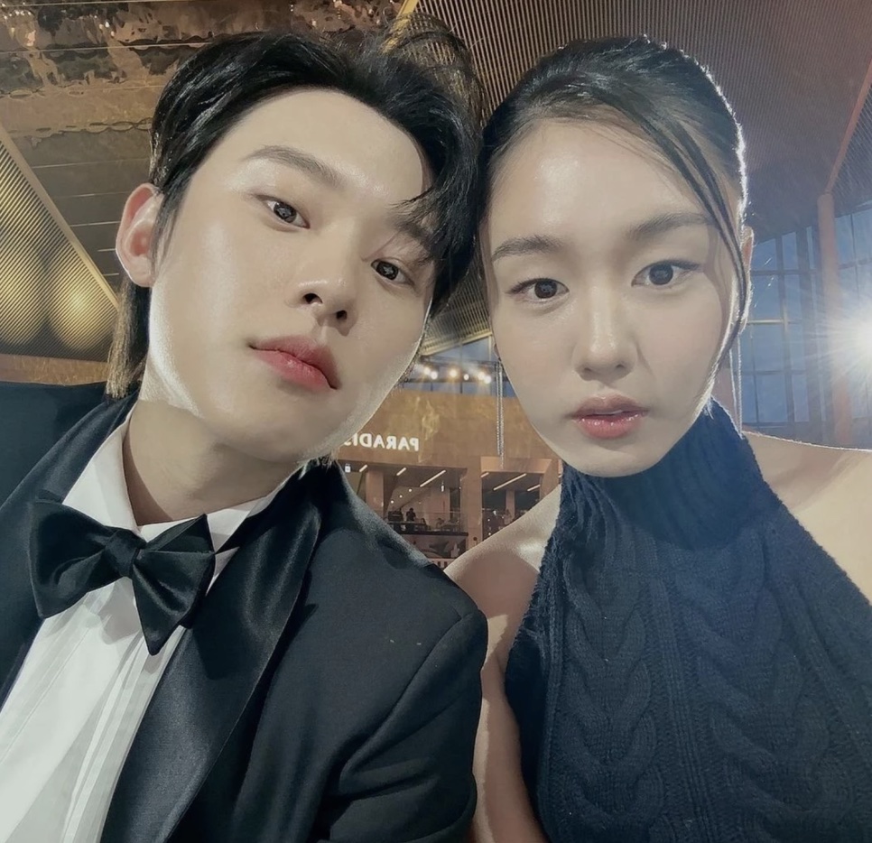 Ahn Eun-jin de blusa preta de gola alta e um colega de smoking, em uma selfie numa noite de premiação