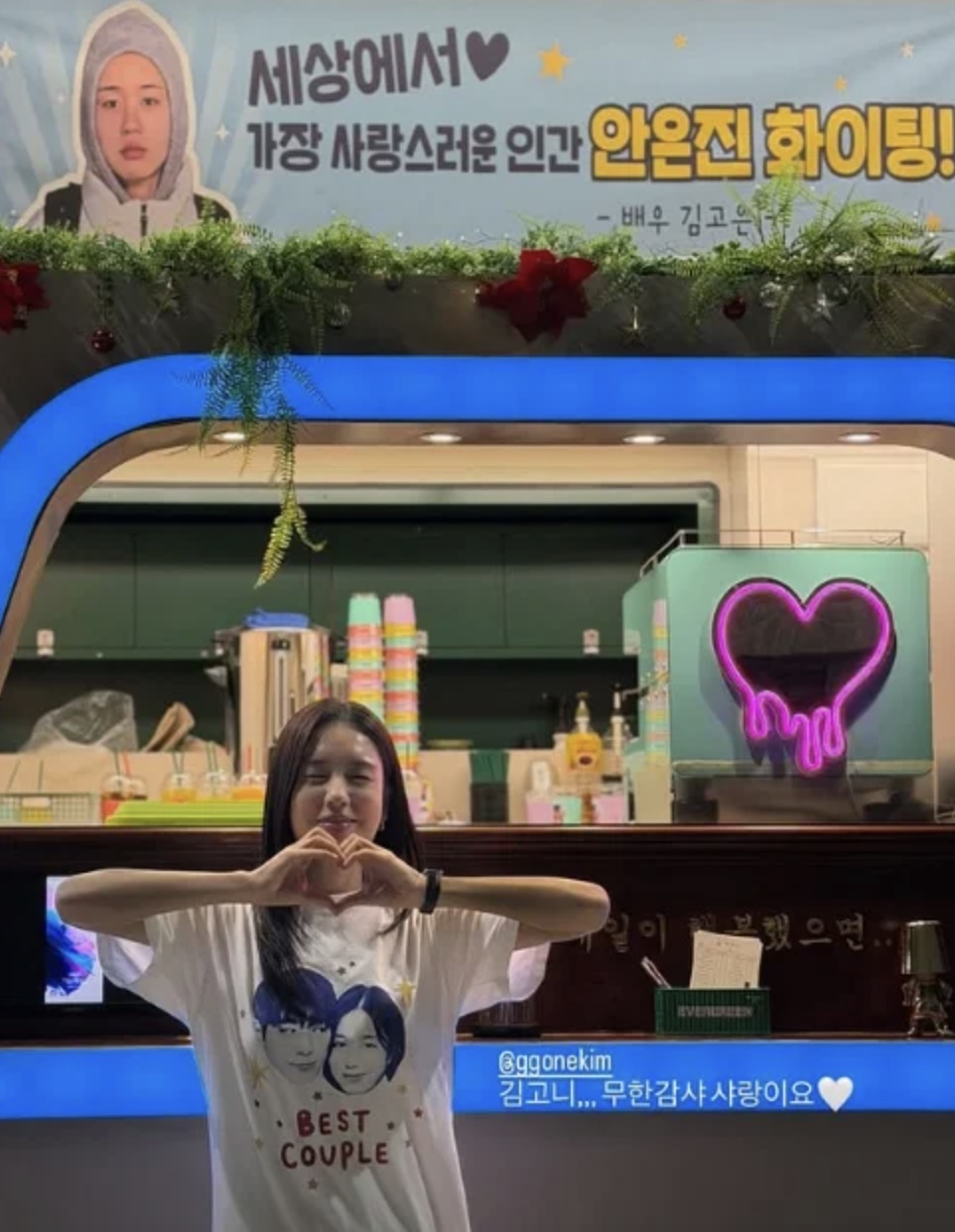 Ahn Eun-jin fazendo coração com as mãos na frente do food truck de café que a Kim Go-eun mandou pro set
