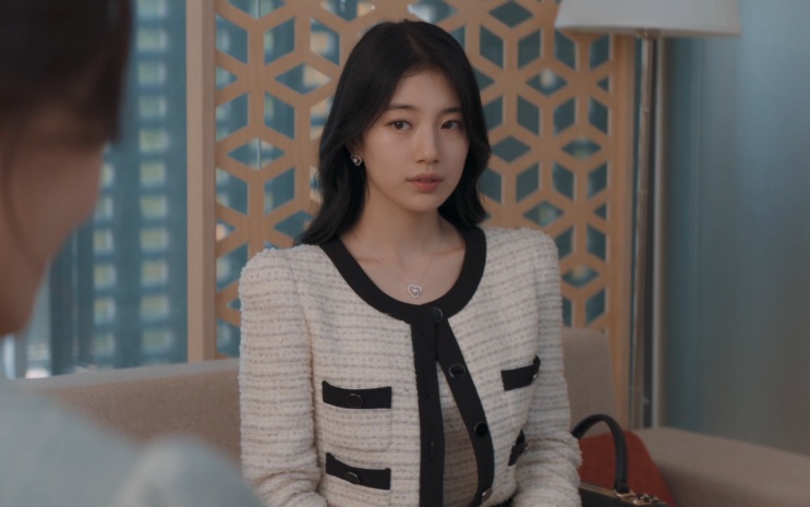 Lee Yu-mi de conjunto de tweed branco, de pé em um saguão de prédio