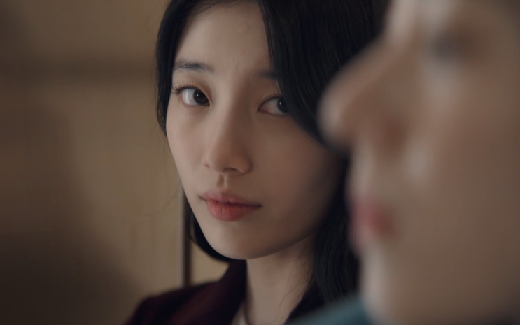 Lee Yu-mi de perfil, ao lado de outra pessoa desfocada em primeiro plano