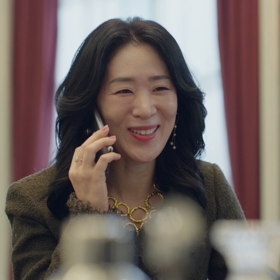 Ok Gye-hui, a diretora da Galeria Cheon, sorrindo ao telefone dentro de casa