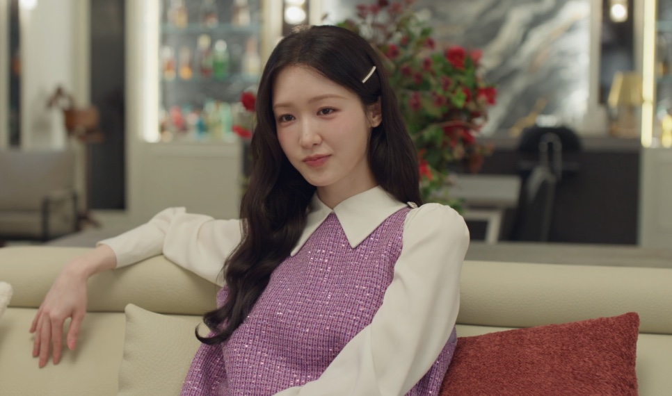Cheon Ha-ri, prima mais nova da Yeo-ri, sentada no sofá da sala com um olhar de canto