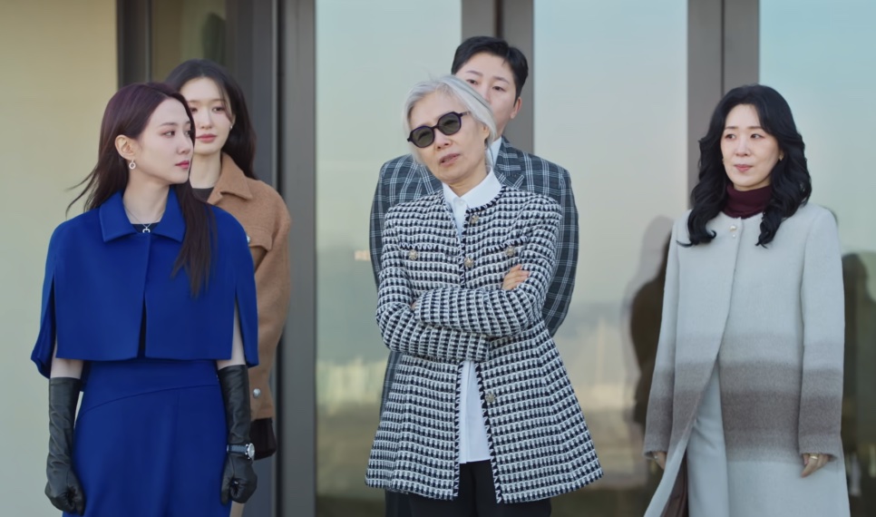 A família reunida num terraço: a Cheon Yeo-ri (Park Eun-bin) de vestido azul, a avó Baek Kyung-ja de óculos escuros no meio e a Ok Gye-hui de casaco claro à direita