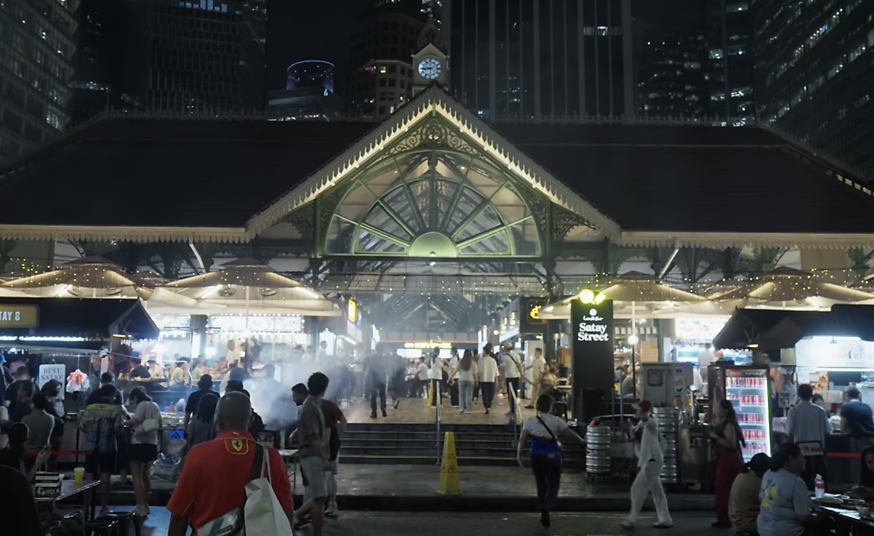 A fachada iluminada do Lau Pa Sat à noite, com muita gente na rua em frente