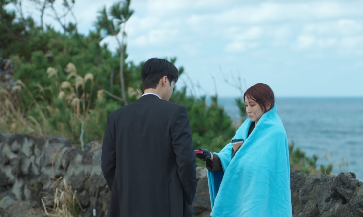 Kang-wook entregando um copo de café para Yeo-ri, enrolada no cobertor azul