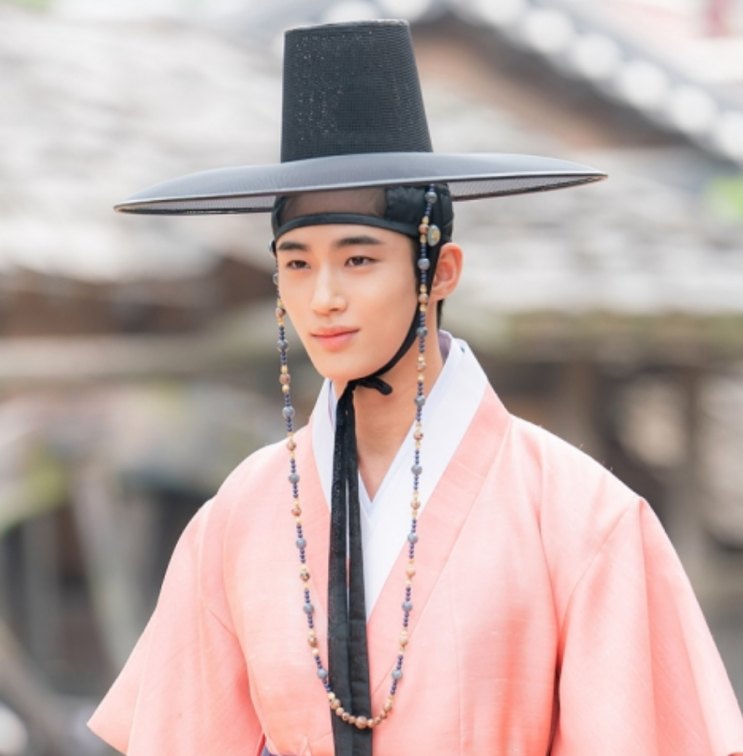 Byeon Woo-seok de hanbok rosa e chapéu tradicional, em cena da série