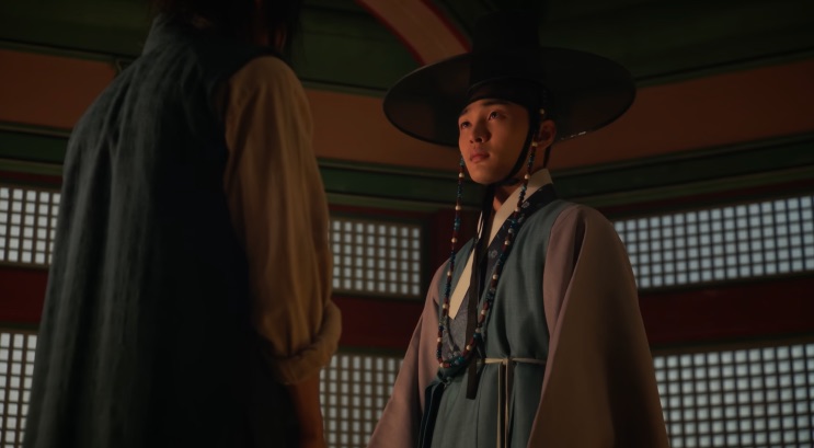 Seo Ji-hoon de hanbok e chapéu, de pé diante de outra pessoa