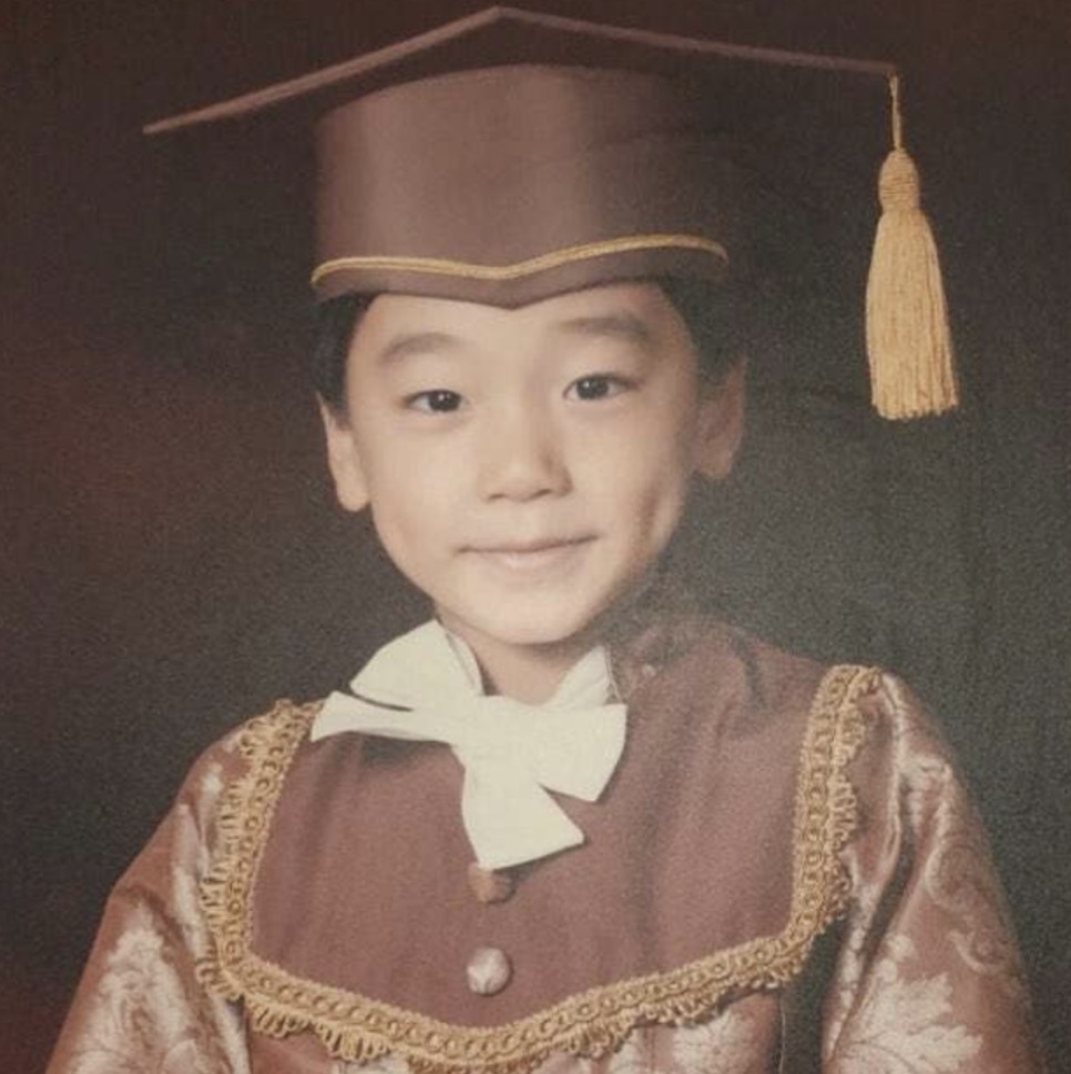 Choi San criança, com beca e capelo de formatura, numa foto antiga