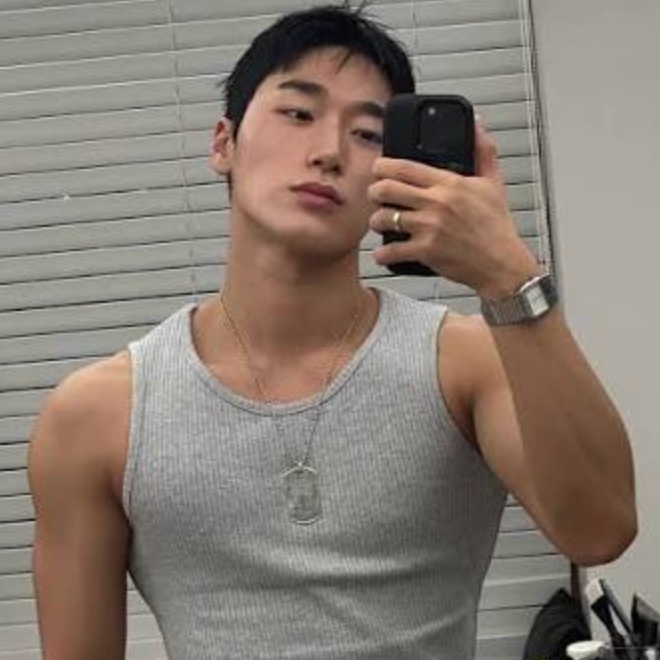 Selfie de Choi San no espelho, de regata cinza, mostrando os ombros