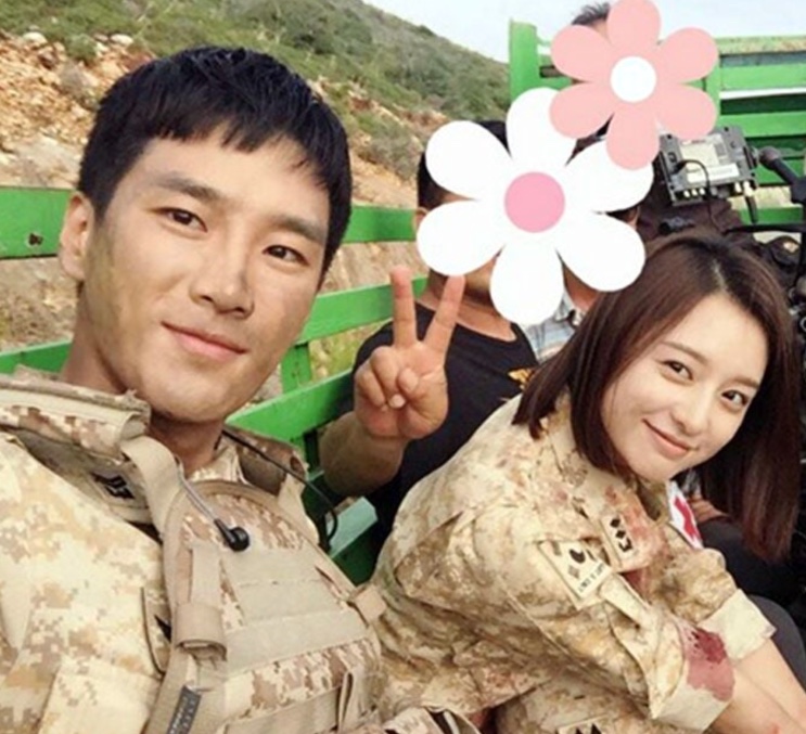 Selfie de Ahn Bo-hyun com Kim Ji-won, os dois de uniforme, num set ao ar livre