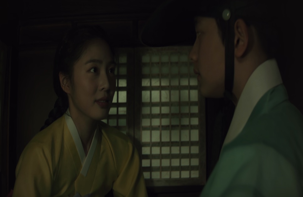 A jovem Cho Yun, de hanbok amarelo, conversando na penumbra com o jovem Cho Won, em Escândalo e Intriga