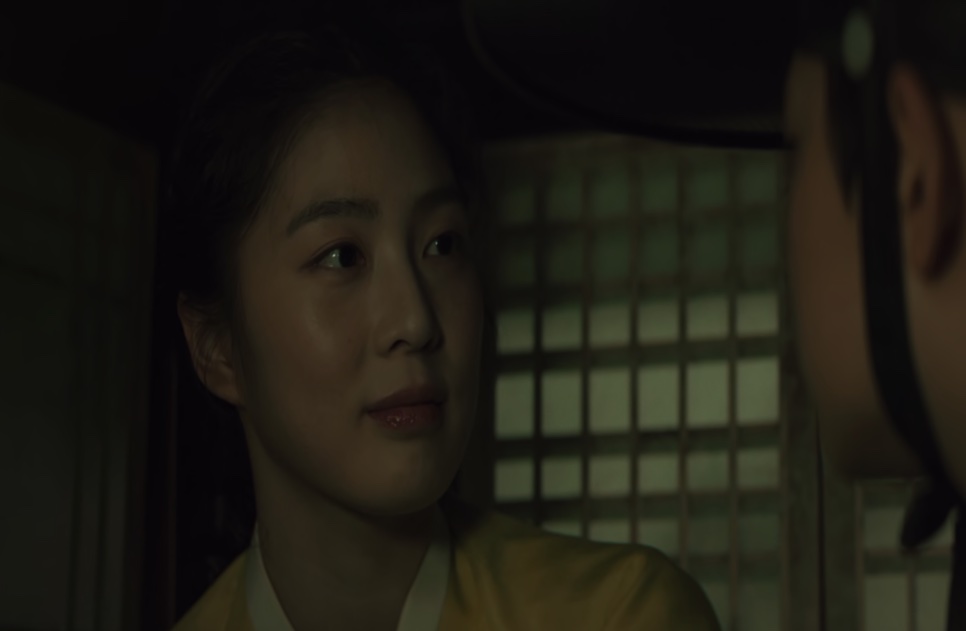 Close da jovem Cho Yun, com um leve sorriso, num quarto escuro, em Escândalo e Intriga