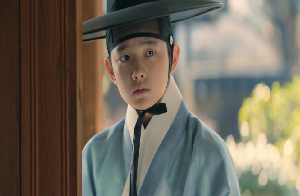 O jovem Cho Won (Jung Hyeon-jun), de chapéu gat preto e roupa azul-clara, em Escândalo e Intriga