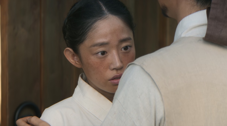 Eun-sil, de hanbok branco, olhando para um homem de costas dentro de um quarto de madeira, em Escândalo e Intriga