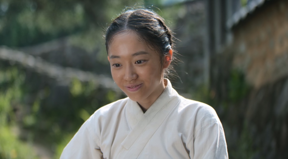 Close da Eun-sil, de hanbok claro e cabelo preso, sorrindo ao sol, em Escândalo e Intriga