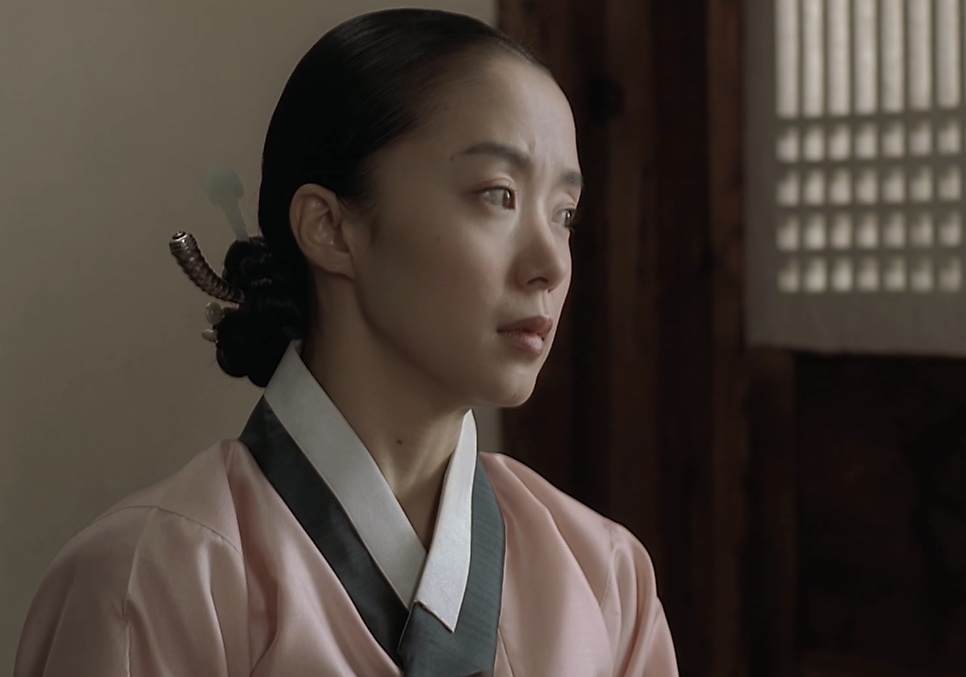 Jeon Do-yeon, no papel da Sukbuin em Untold Scandal, de hanbok rosa-claro e cabelo preso, olhando para o lado