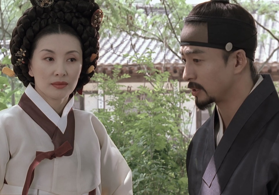 A Senhora Jo, de hanbok claro, ao lado do Jo-won num jardim, em Untold Scandal