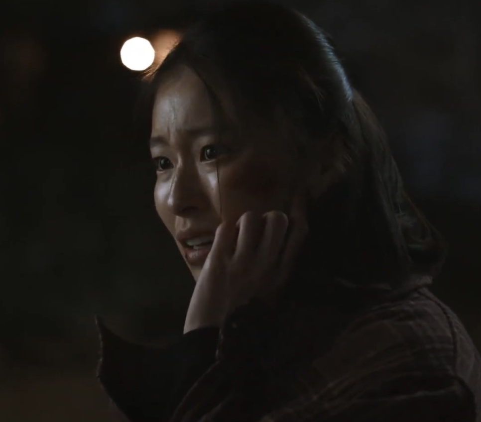 Lee Jeong-ok à noite, com o rosto machucado, levando a mão ao rosto, na série Oasis