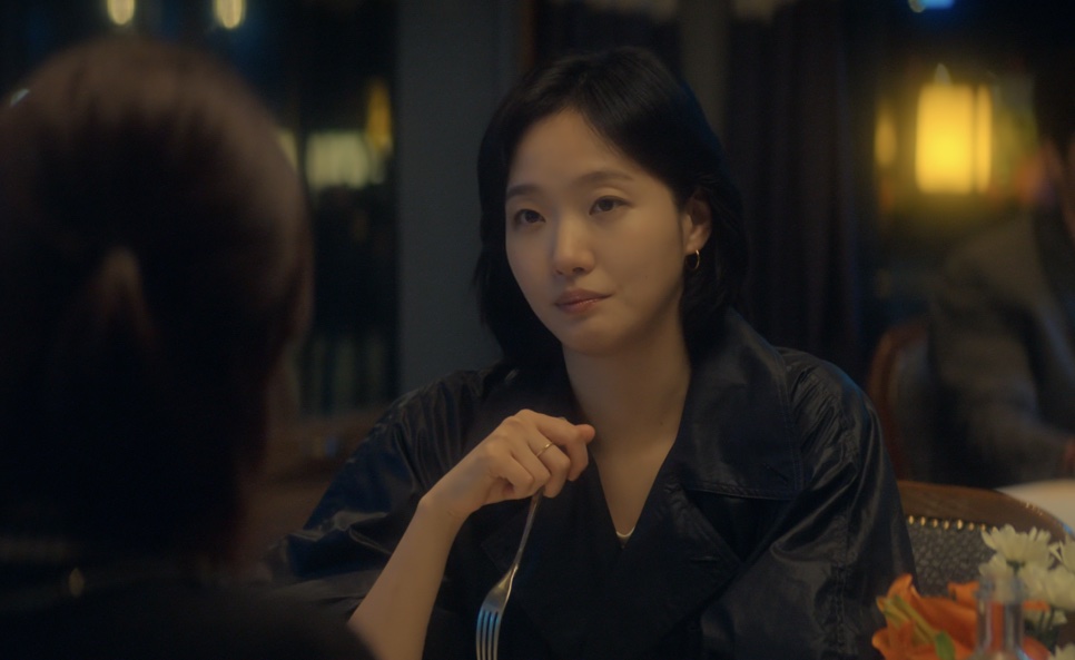 Eun-jung (Kim Go-eun) à mesa de um restaurante, com o garfo na mão, ouvindo a amiga do outro lado