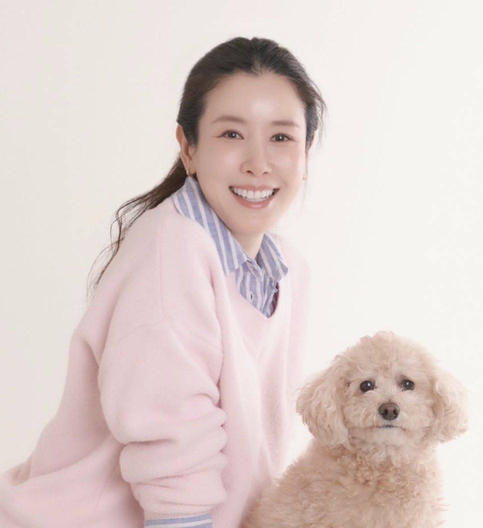 Lee Tae-ran sorrindo de suéter rosa, ao lado de um poodle bege
