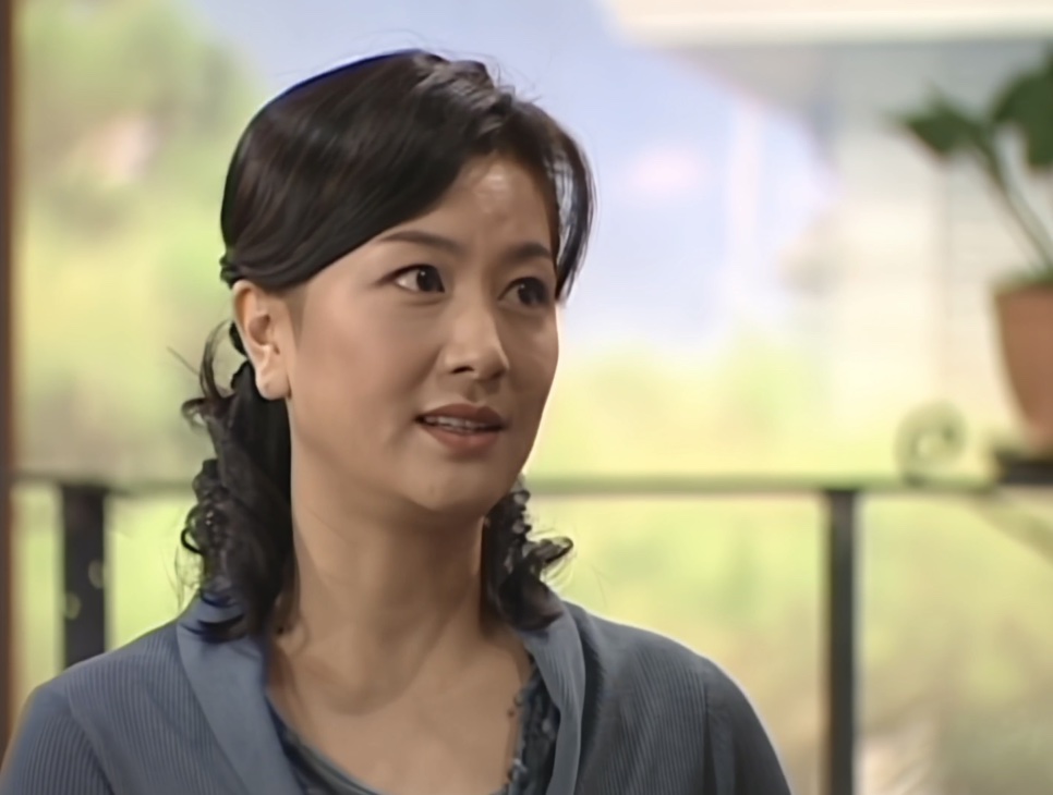 Kim Hye-sun de cardigã cinza conversando numa varanda, no papel de Na Deok-chil