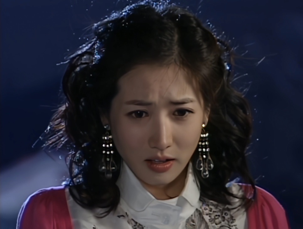 Choi Jung-won de cabelo cacheado e brincos grandes, com cara de choro numa cena noturna, no papel de Na Mi-chil
