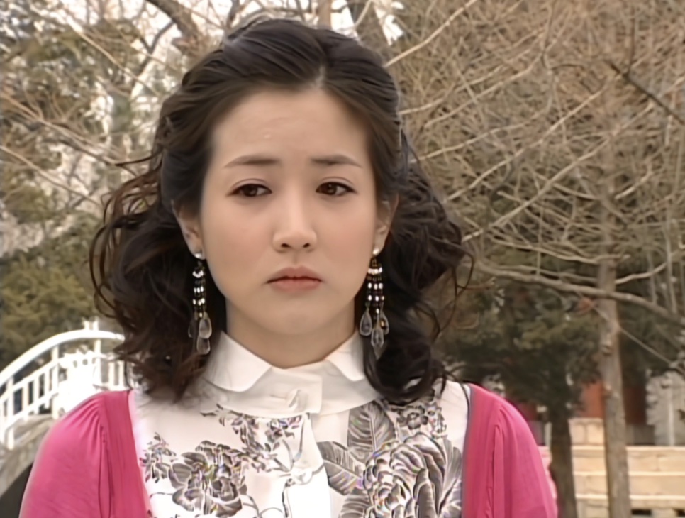 Choi Jung-won de cardigã rosa com cara triste num parque, no papel de Na Mi-chil