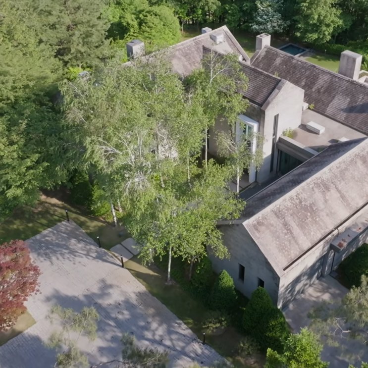 Vista aérea da Piet Boon House, uma casa baixa de pedra cercada de árvores